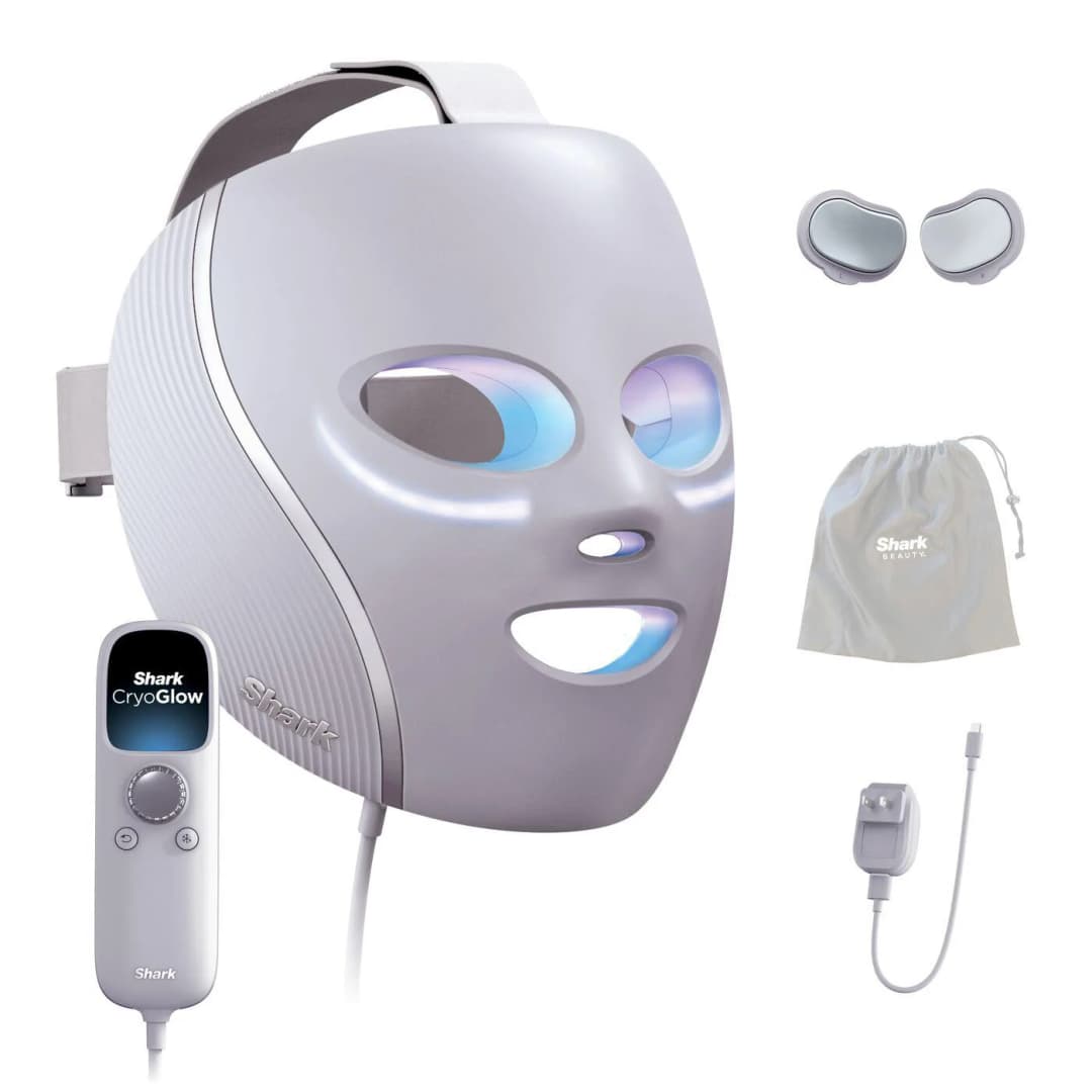 Eine graue Shark CryoGlow Gesichtsmaske mit Zubehör: Augenpads, Beutel, Fernbedienung und Ladegerät. Die Maske hat blaue Lichter.