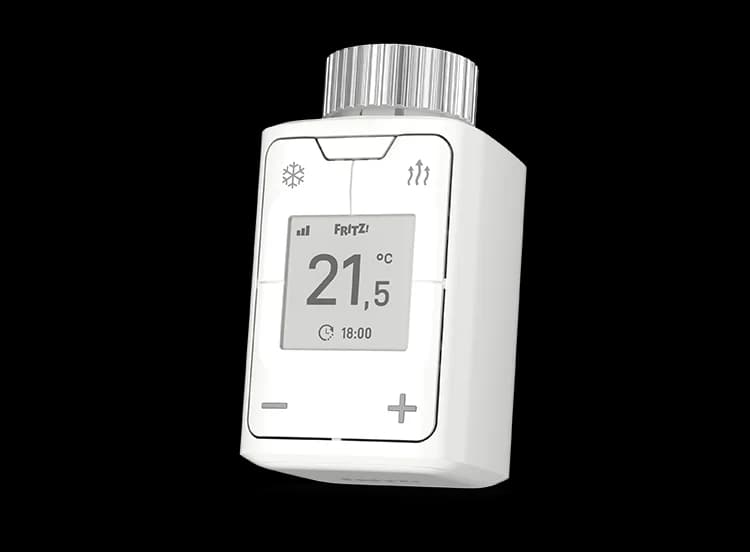 Ein weißes Smart-Thermostat mit Digitalanzeige, die 21,5 Grad Celsius und die Uhrzeit anzeigt. Es hat Plus- und Minus-Tasten.