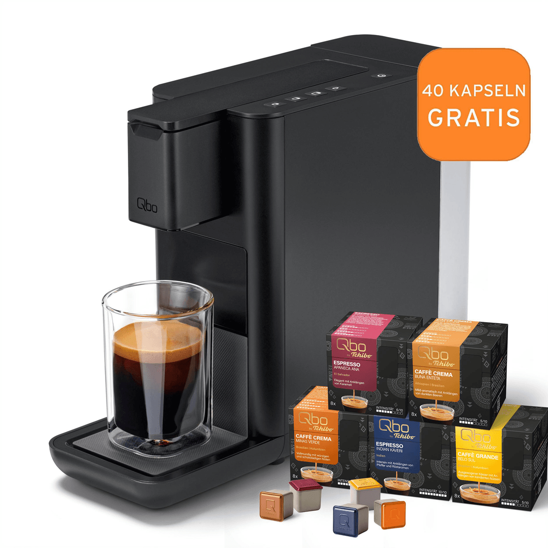 Eine Kaffeemaschine mit einem Glas Espresso und Kapselpackungen. Orangefarbene Tafel mit '40 KAPSELN GRATIS'.